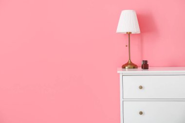 Odada renkli duvarın yanında modern çekmeceler ve lambalar var.