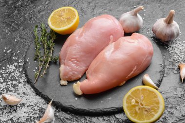 Koyu arkaplanda çiğ tavuk filetosu olan tahta