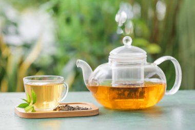 Teapot and cup of hot tea on table outdoors