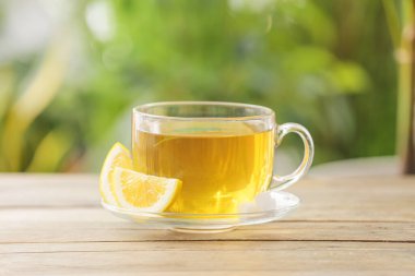 Cup of green tea with lemon on table outdoors