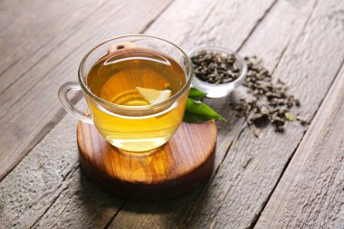 Cup of green tea and dry leaves on wooden background