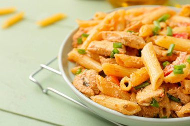 Plate with cajun chicken pasta on color wooden background, closeup