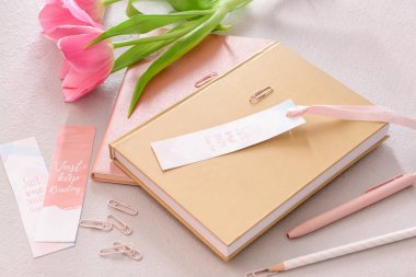 Açık arkaplan üzerinde yer imleri, kırtasiye ve çiçek bulunan kitaplar