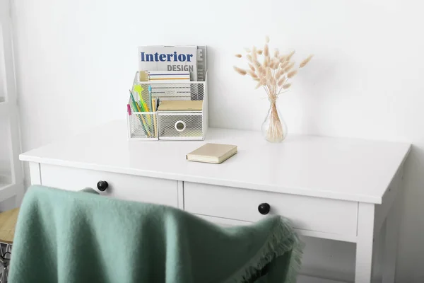 Stylish organizer with stationery and magazine on table in room