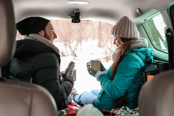 冬の日に車の中で熱いお茶を飲む幸せな若いカップル — ストック写真