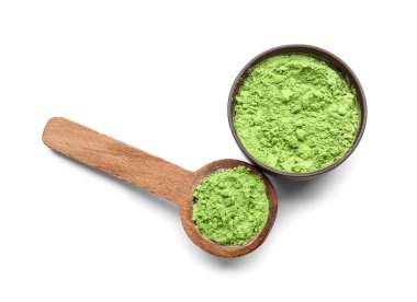 Beyaz arka planda pudralanmış kibrit çayı ile kase ve kaşık.