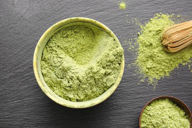 Koyu arkaplanda pudralı kibrit çayı ve chasen tabakları, yakın plan.