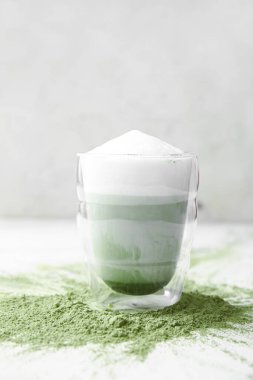 Bir bardak dalgona matcha latte ve hafif arkaplanda pudra