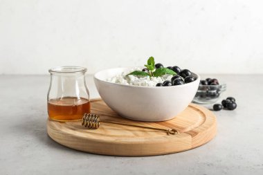 Hafif arka planda yabanmersinli bir kase doğal süzme peynir.