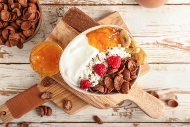 Mısır gevreği ve ahududu arkaplanlı bir kase süzme peynir.