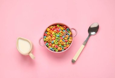 Renkli mısır gevreği halkaları, kaşık ve sütle dolu bir kase