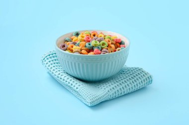 Renkli arkaplanda lezzetli mısır gevreği halkaları olan bir kase