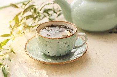 Açık arkaplanda bir fincan sıcak yeşil çay