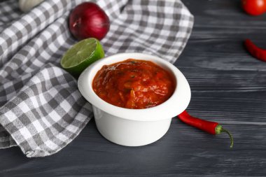 Koyu ahşap arka planda bir kase lezzetli salsa sosu