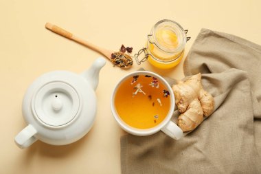 Çaydanlık ve çay, zencefil ve bal rengi arka planda.
