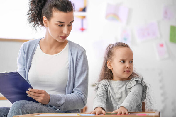 Female psychologist working with little girl at home