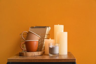 Masada renk arkaplanına karşı mum, fincan ve defterler yakılıyor