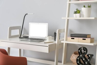 Odadaki ışık duvarının yanında dizüstü bilgisayarı olan rahat bir iş yeri.