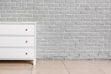 Odadaki tuğla duvarın yanındaki modern çekmeceler.