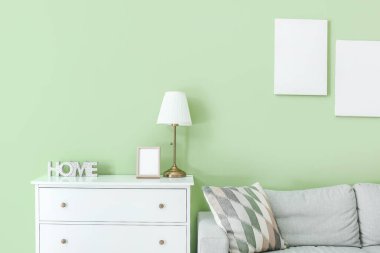 Oda duvarının yanında lamba ve kanepe olan çekmeceler.