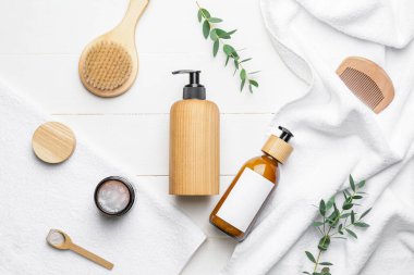 Doğal şampuanlı şişeler, hafif arka planda tarak ve fırça