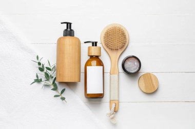 Doğal şampuanlı şişeler ve hafif ahşap arka planda fırçalar.