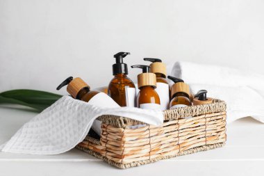 Açık ahşap arka planda doğal şampuan şişeleriyle dolu bir sepet.