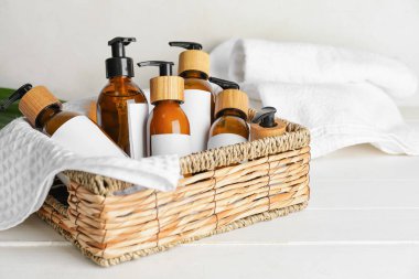 Açık ahşap arka planda doğal şampuan şişeleriyle dolu bir sepet.