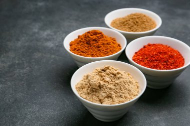 Koyu arkaplanda farklı baharatlar bulunan kaseler