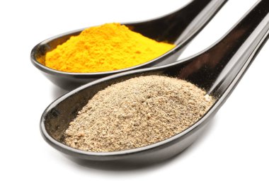 Beyaz arka planda zerdeçal ve biber tozlu kaşıklar, yakın plan.