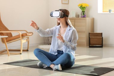 Evde sanal gerçeklik gözlüklü genç bir kadın var.