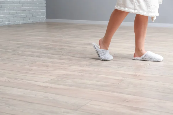 Woman in slippers walking on new laminate flooring at home