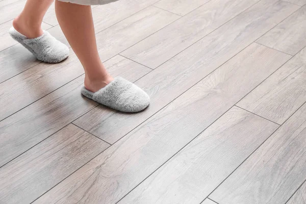 Woman in slippers walking on new laminate flooring at home