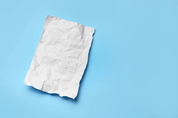 Blank crumpled sheet of paper on color background