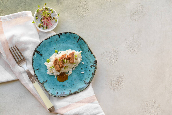 Тарелка с вкусным рисом и мясом на светлом фоне