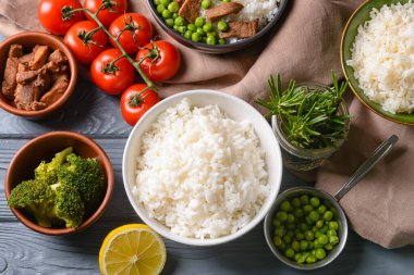 Lezzetli pirinçli kaseler ve siyah ahşap arka planda sebzeler.
