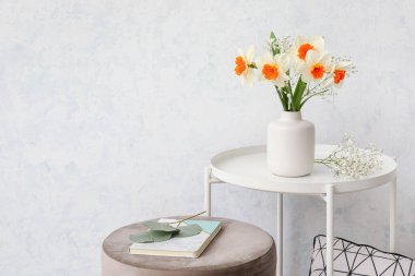 Masada nergis çiçekleri olan bir vazo.