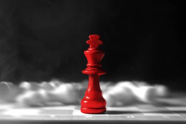 Kırmızı satranç taşı, karanlık arka plana karşı dama tahtasındaki sıradan taşlar arasında