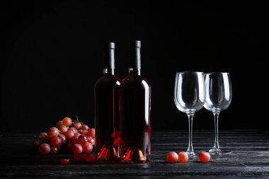 Karanlık arka planda kadehler ve şarap şişeleri.