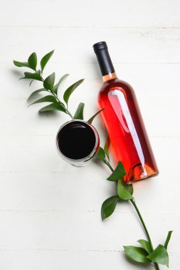 Beyaz ahşap arka planda bir şişe ve bir bardak şarap.