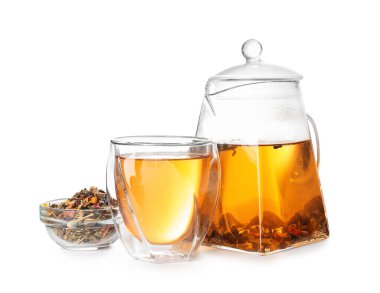 Çaydanlık, bir bardak çay ve beyaz arka planda kuru yapraklar.