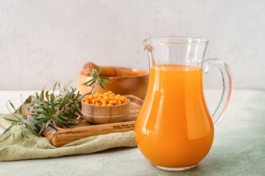 Hafif arka planda bir sürahi sağlıklı deniz dikeni suyu.