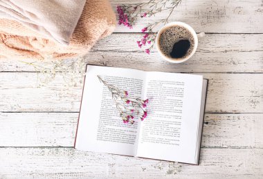 Taze çiçekli kitap ve masada bir fincan kahve.