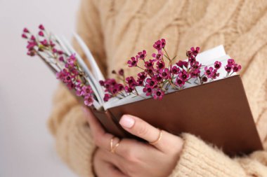 Elinde taze çiçekli kitap tutan kadın, yakın plan.