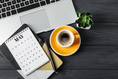 Bilgisayarlı kağıt takvim, masada kahve ve kırtasiye malzemesi.