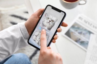 Cep telefonlu genç bir kadın evde e-postalarını kontrol ediyor, kapatıyor.