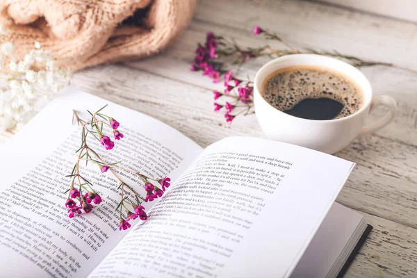 Taze çiçekli kitap ve masada bir fincan kahve.