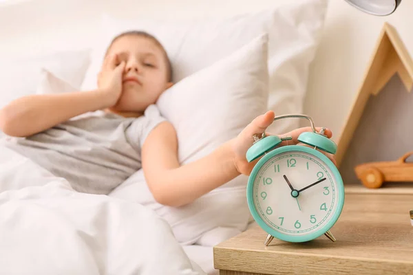 目覚まし時計をオフに眠そうな男の子の朝 — ストック写真
