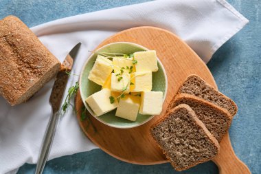 Taze tereyağlı kase ve ahşap arka planda ekmek.