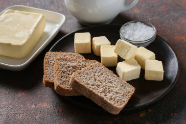 Taze tereyağlı tabak, ekmek ve tuz arkaplanda.